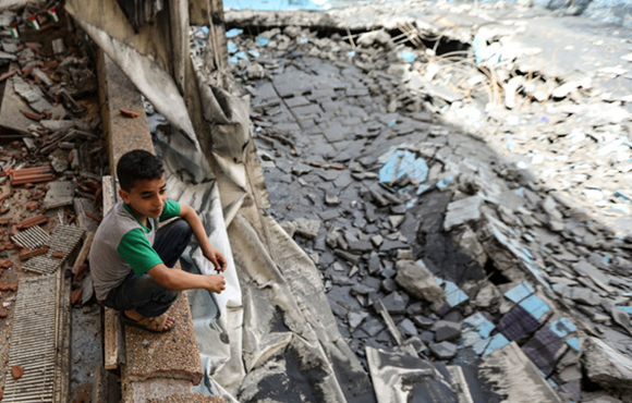 Niño en Gaza sentado en medio de los escombros