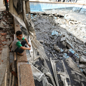 Niño sentado en medio de los escombros causados por los ataques
