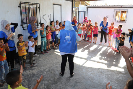 Niños refugiados de un campamento en cículo jugando con los voluntarios y trabajadores de Islamic Relief