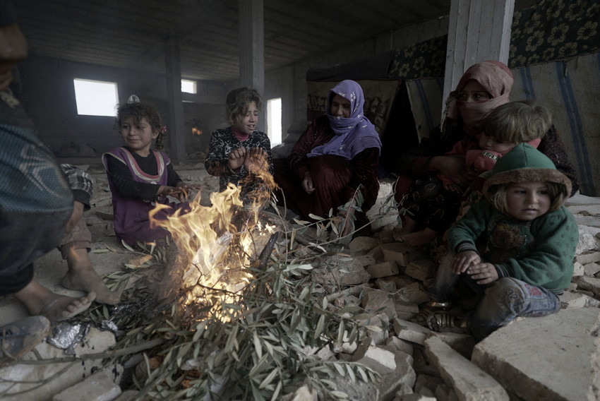Niños refugiados calentándose al fuego de una hoguera