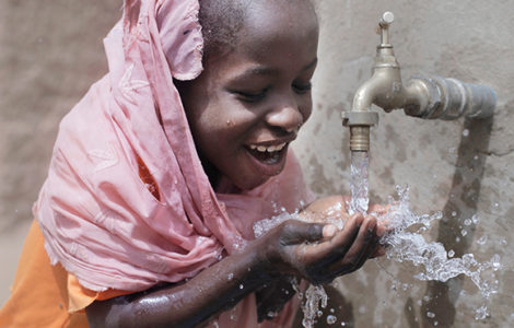 Niña bebiendo agua de una fuente