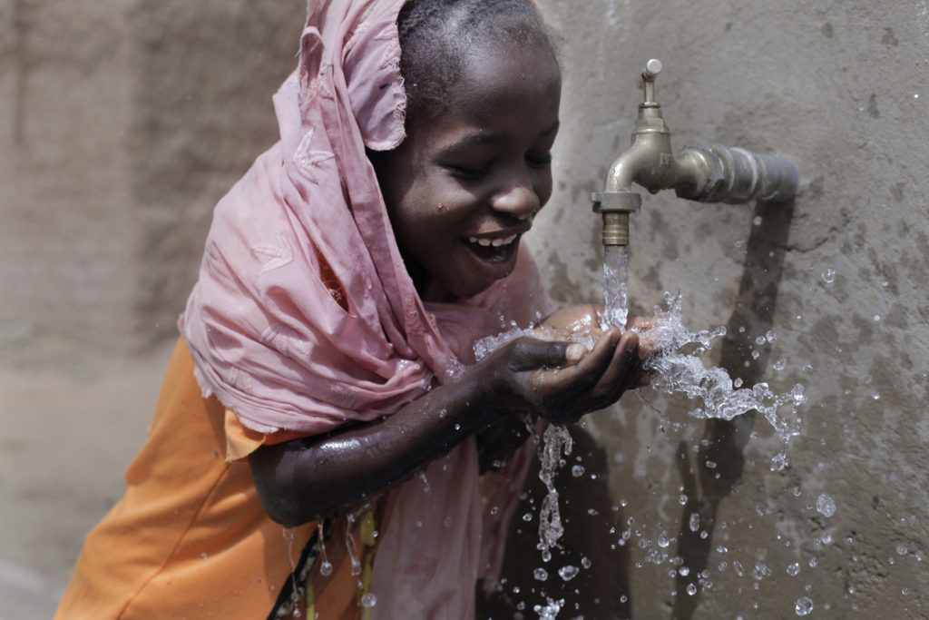 Niña nigeriana bebiendo agua