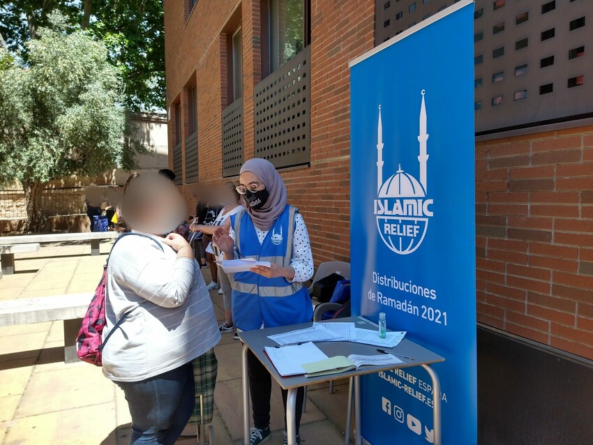 Voluntaria de Islamic Relief entregando un vale de alimentos