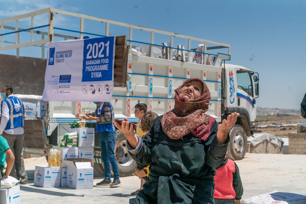 En Siria, una mujer da gracias a Dios al recibir un paquete de alimentos a través del programa de Ramadán de Islamic Relief, el cual el año pasado llegó a 934.000 personas en 31 países.